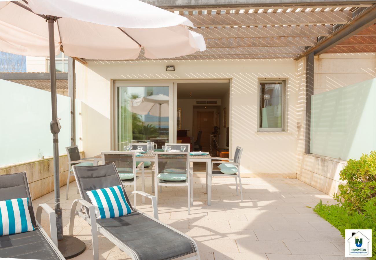 Terrace with sun beds and umbrellas in La Nau B Terrace of the apartment with umbrella and access to the pool